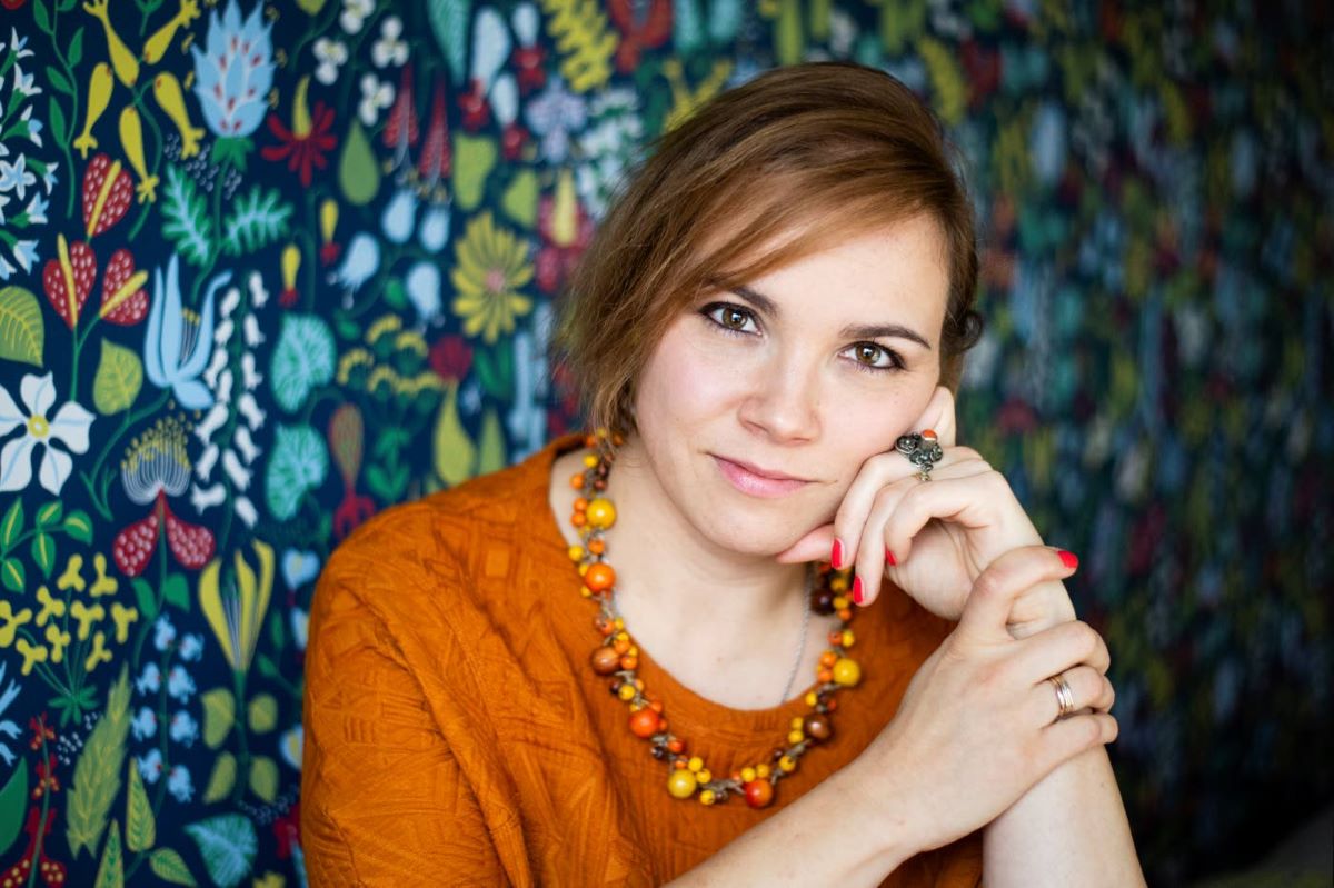 Naiskirjailija Anna Soudakovan kasvokuva. Hän nojaa vasempaan käteensä ja katsoo kameraan.